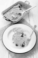 home made cherry crumble on enamel plate with fork, mug and baking tin
