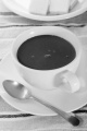 hot chocolate in white cup with spoon and waffles on a plate in the background