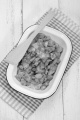 traditional hungarian meal potato and pasta with paprika powder and bacon bits in enamel bowl and wooden spatula